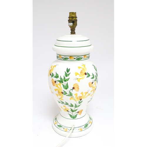 1676 - A late 20thC ceramic table lamp the white ground decorated with yellow and green floral decoration. ... 