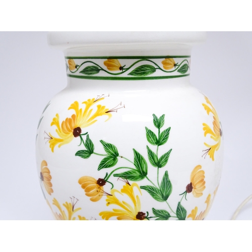 1676 - A late 20thC ceramic table lamp the white ground decorated with yellow and green floral decoration. ... 