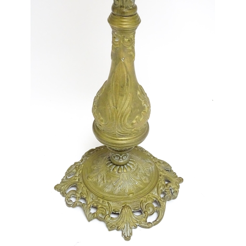 1701 - A Victorian brass oil lamp with floral and scroll detail, cranberry pink reservoir and shade. Approx... 