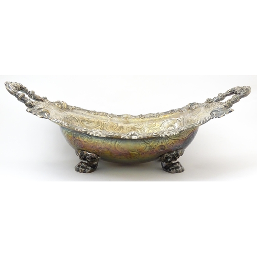 630 - A large George III silver twin handled dish with floral and C scroll decoration and raised on four l... 