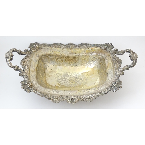 630 - A large George III silver twin handled dish with floral and C scroll decoration and raised on four l... 