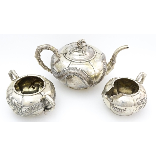 638 - Chinese Export Silver: A late 19th / early 20thC white metal three piece tea set with relief dragon ... 