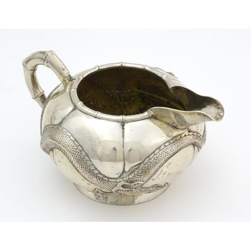 638 - Chinese Export Silver: A late 19th / early 20thC white metal three piece tea set with relief dragon ... 