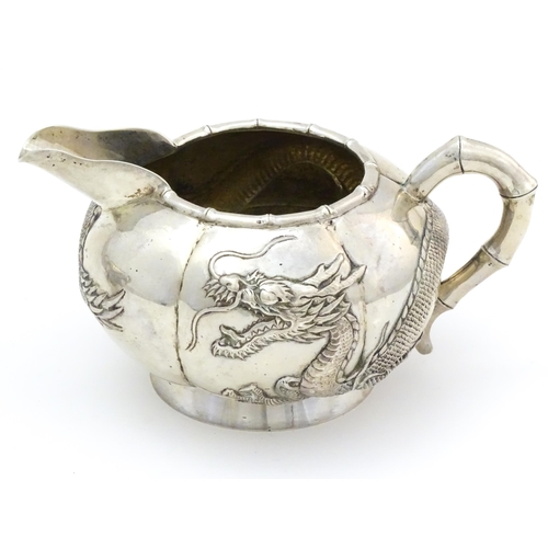 638 - Chinese Export Silver: A late 19th / early 20thC white metal three piece tea set with relief dragon ... 