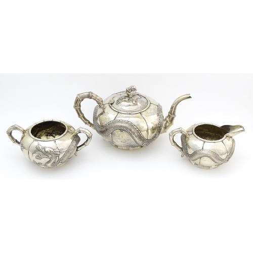 638 - Chinese Export Silver: A late 19th / early 20thC white metal three piece tea set with relief dragon ... 