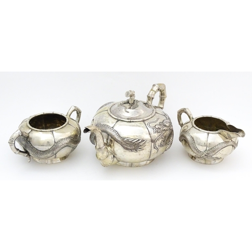 638 - Chinese Export Silver: A late 19th / early 20thC white metal three piece tea set with relief dragon ... 