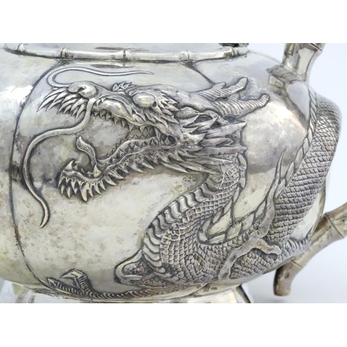 638 - Chinese Export Silver: A late 19th / early 20thC white metal three piece tea set with relief dragon ... 