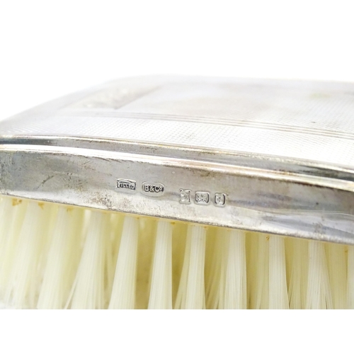 653 - A cased silver brush with engine turned decoration and a silver mounted comb, hallmarked Birmingham ... 