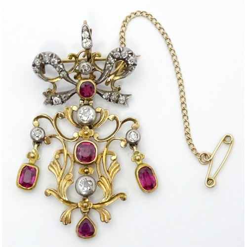 787 - A Belle Epoque pendant set with scrolling detail set with rubies and diamonds surmounted by a bow se... 