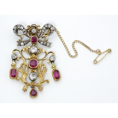 787 - A Belle Epoque pendant set with scrolling detail set with rubies and diamonds surmounted by a bow se... 