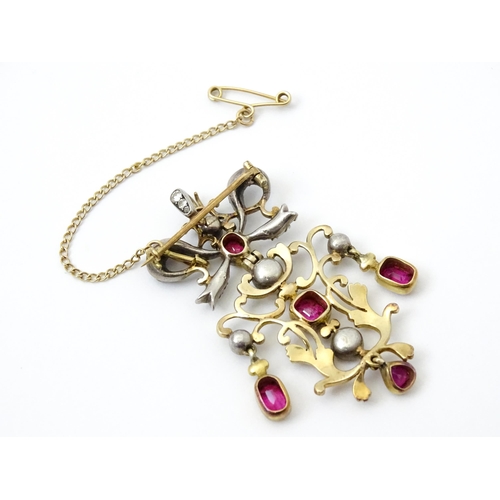 787 - A Belle Epoque pendant set with scrolling detail set with rubies and diamonds surmounted by a bow se... 