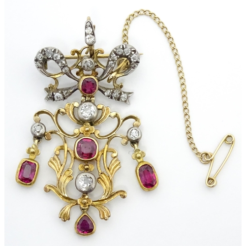 787 - A Belle Epoque pendant set with scrolling detail set with rubies and diamonds surmounted by a bow se... 