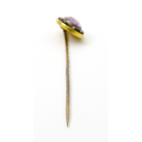 795 - A late 19thC / early 20thC yellow metal stick pin set with Amethyst bordered by seed pearls. Approx ... 