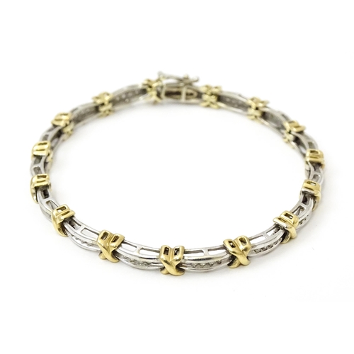 822 - A white metal bracelet marked 10k with yellow metal detail and set with diamonds. Approx 7 1/4