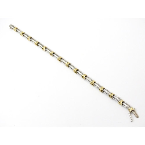 822 - A white metal bracelet marked 10k with yellow metal detail and set with diamonds. Approx 7 1/4