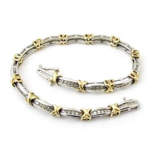 822 - A white metal bracelet marked 10k with yellow metal detail and set with diamonds. Approx 7 1/4