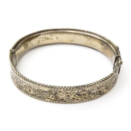 827 - A silver bracelet of bangle form with engraved decoration. Hallmarked Birmingham 1977 with Silver Ju... 