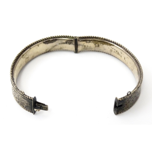 827 - A silver bracelet of bangle form with engraved decoration. Hallmarked Birmingham 1977 with Silver Ju... 