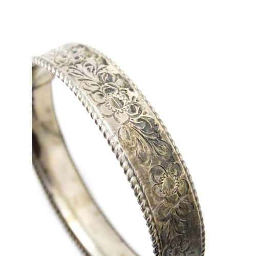 827 - A silver bracelet of bangle form with engraved decoration. Hallmarked Birmingham 1977 with Silver Ju... 