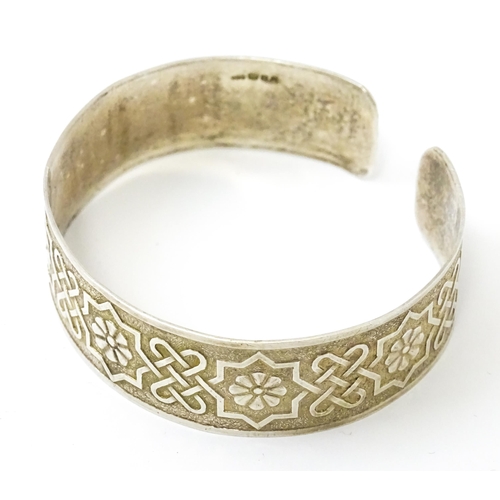 828 - A silver bracelet of cuff bangle form with geometric decoration.  Hallmarked London 1972 LRD.