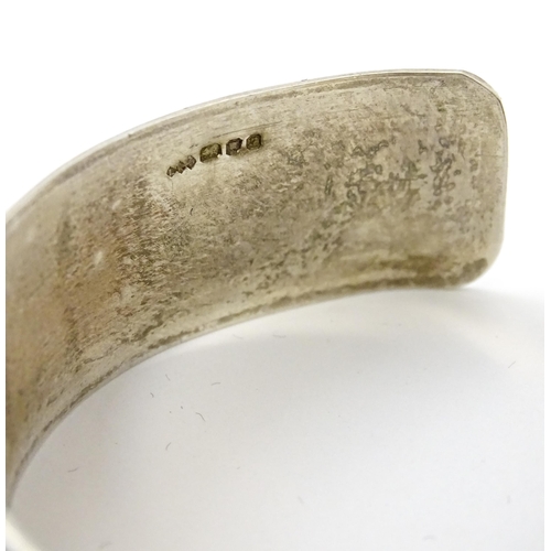 828 - A silver bracelet of cuff bangle form with geometric decoration.  Hallmarked London 1972 LRD.