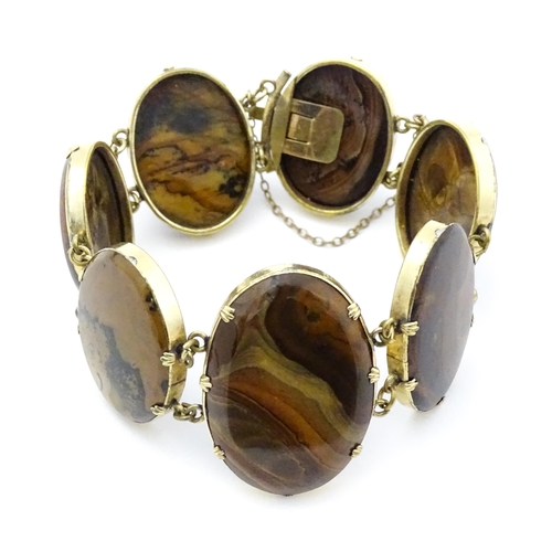 830 - A yellow metal bracelet set with seven graduated agate cabochons. Approx. 7 1/2