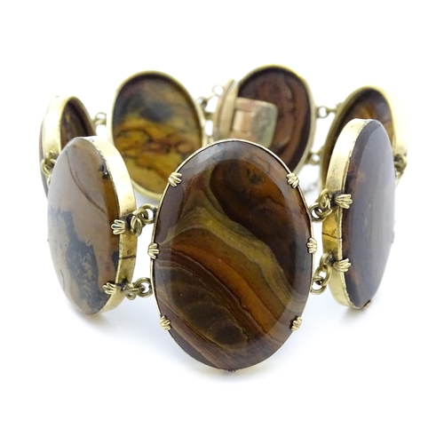 830 - A yellow metal bracelet set with seven graduated agate cabochons. Approx. 7 1/2