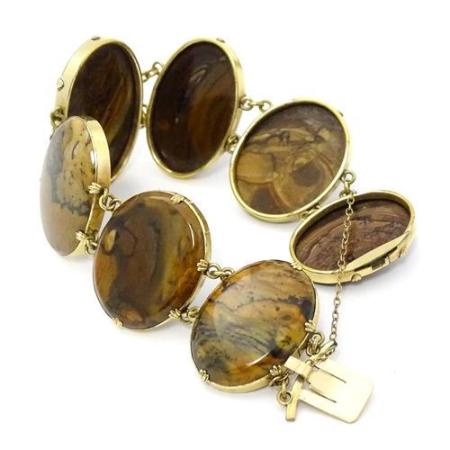 830 - A yellow metal bracelet set with seven graduated agate cabochons. Approx. 7 1/2