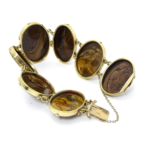 830 - A yellow metal bracelet set with seven graduated agate cabochons. Approx. 7 1/2