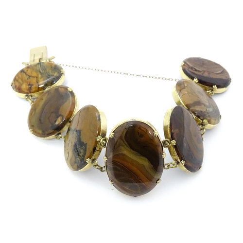 830 - A yellow metal bracelet set with seven graduated agate cabochons. Approx. 7 1/2