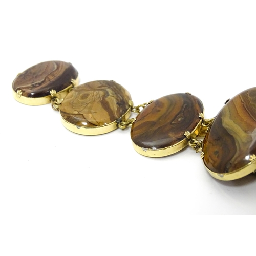 830 - A yellow metal bracelet set with seven graduated agate cabochons. Approx. 7 1/2