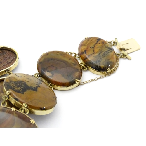 830 - A yellow metal bracelet set with seven graduated agate cabochons. Approx. 7 1/2