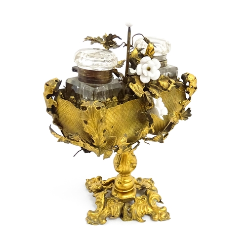 1426 - An unusual French 19thC gilt metal inkstand with scrolling foliate decoration and porcelain flowers,... 