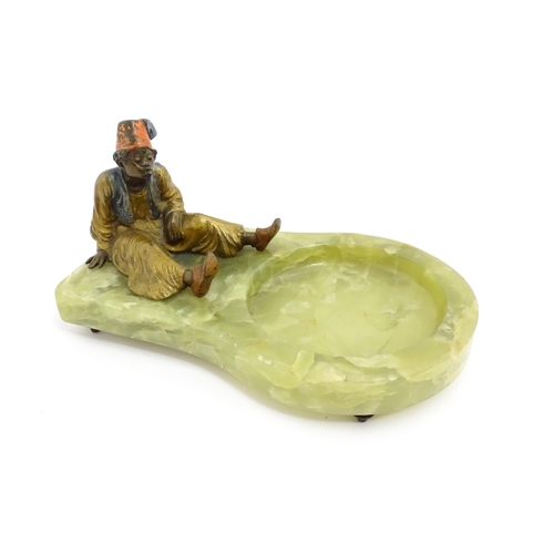 1429 - An early 20thC onyx ashtray surmounted by a cold painted bronze model of a seated Arab boy smoking. ... 