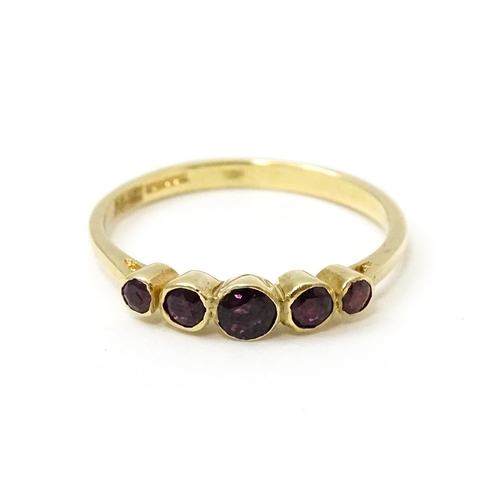 727 - A 9ct gold ring set with purple red coloured stones. Ring size approx. R