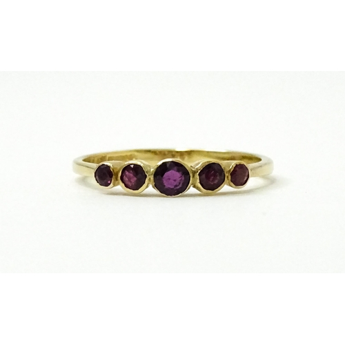 727 - A 9ct gold ring set with purple red coloured stones. Ring size approx. R