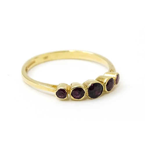 727 - A 9ct gold ring set with purple red coloured stones. Ring size approx. R