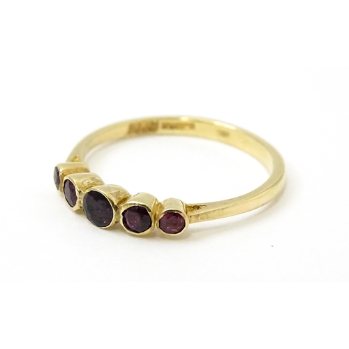 727 - A 9ct gold ring set with purple red coloured stones. Ring size approx. R