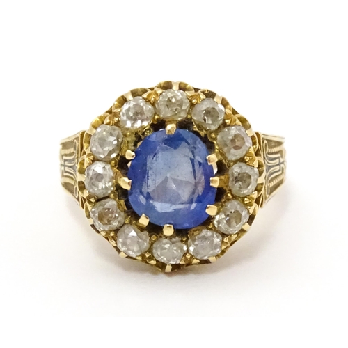 731 - A late 19thC / early 20thC gold ring set with central sapphire bordered by twelve diamonds flanked b... 