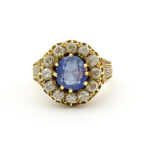 731 - A late 19thC / early 20thC gold ring set with central sapphire bordered by twelve diamonds flanked b... 