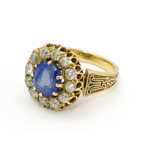 731 - A late 19thC / early 20thC gold ring set with central sapphire bordered by twelve diamonds flanked b... 