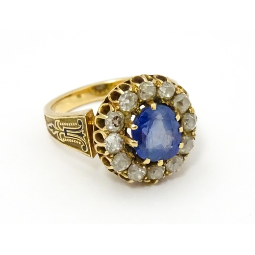 731 - A late 19thC / early 20thC gold ring set with central sapphire bordered by twelve diamonds flanked b... 