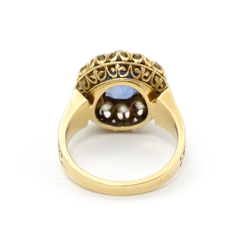 731 - A late 19thC / early 20thC gold ring set with central sapphire bordered by twelve diamonds flanked b... 