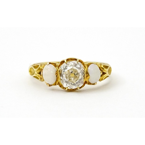 733 - A late 19thC / early 20thC gold ring set with central diamond flanked by opals. The central diamond ... 