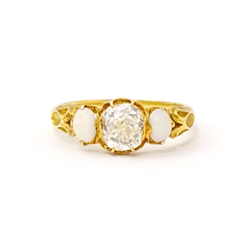 733 - A late 19thC / early 20thC gold ring set with central diamond flanked by opals. The central diamond ... 