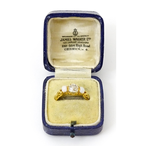 733 - A late 19thC / early 20thC gold ring set with central diamond flanked by opals. The central diamond ... 