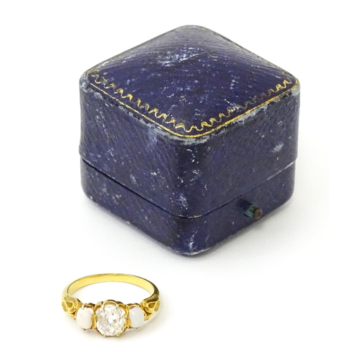 733 - A late 19thC / early 20thC gold ring set with central diamond flanked by opals. The central diamond ... 