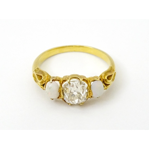 733 - A late 19thC / early 20thC gold ring set with central diamond flanked by opals. The central diamond ... 