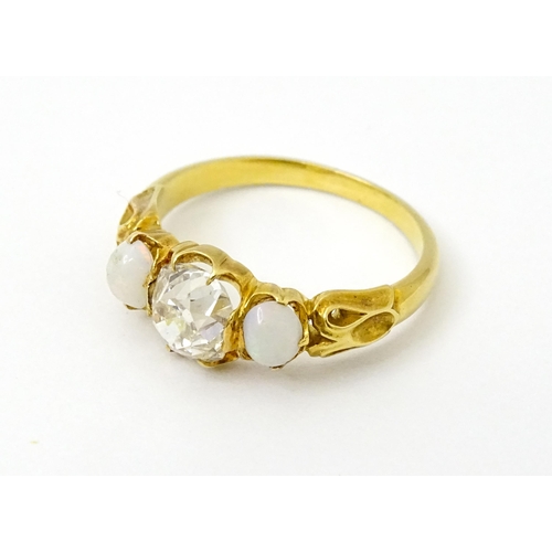 733 - A late 19thC / early 20thC gold ring set with central diamond flanked by opals. The central diamond ... 