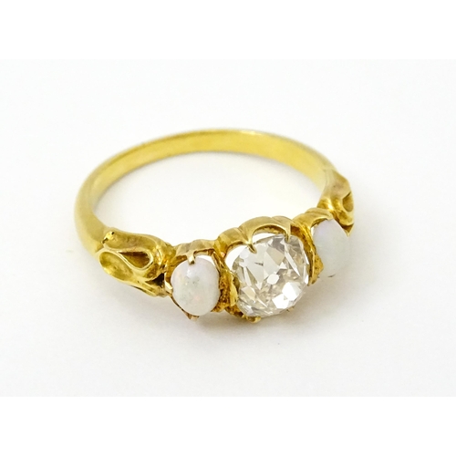 733 - A late 19thC / early 20thC gold ring set with central diamond flanked by opals. The central diamond ... 